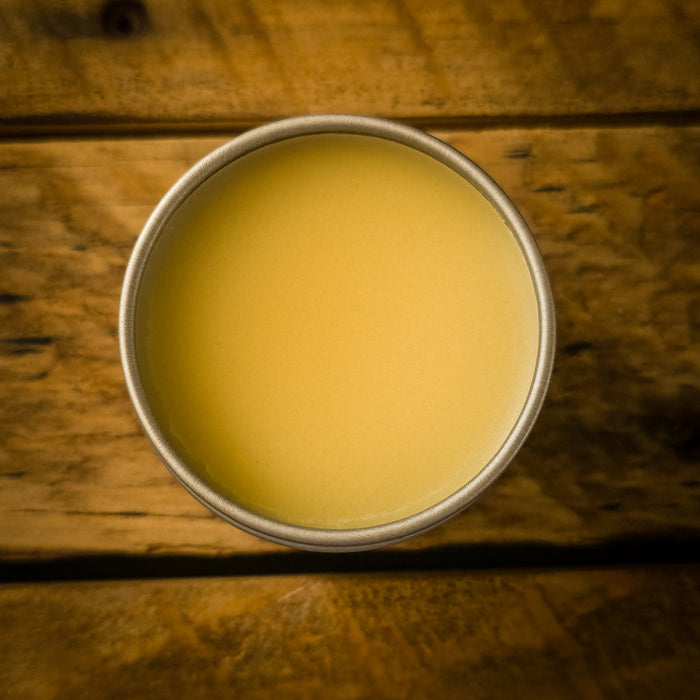 Close-up of Mammoth Beard Co. beard balm in a metal tin, showing its creamy texture ready to be scooped and applied for conditioning and styling.