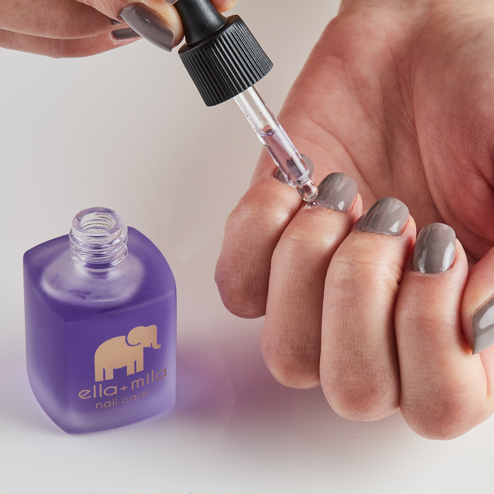 Applying Oil Me Up cuticle oil to the cuticles with the dropper