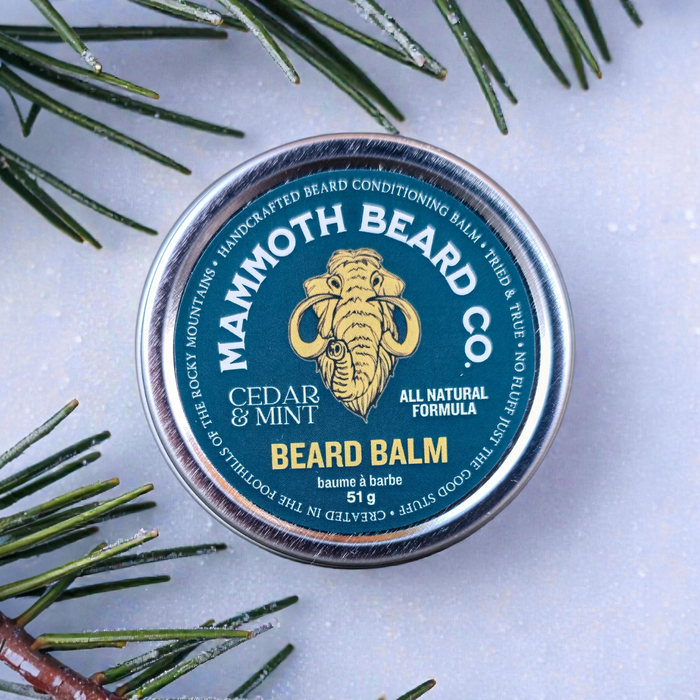 Mammoth Beard Co. beard balm tin with cedar and mint scent on a light background with greenery.