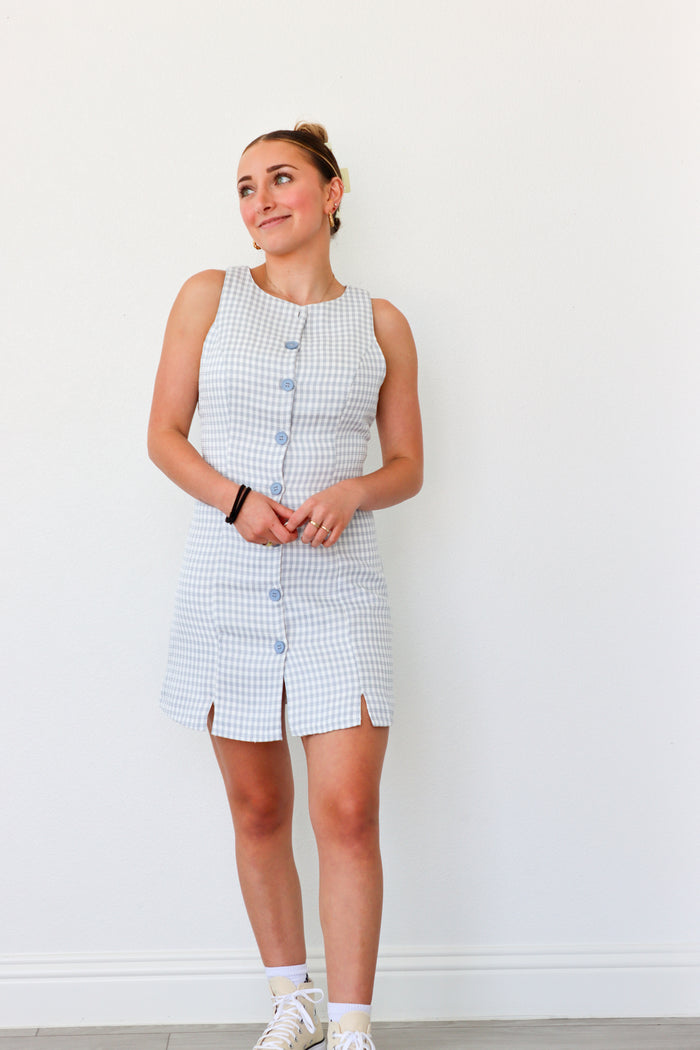 Woman wearing a checkered dress with buttons against a white background