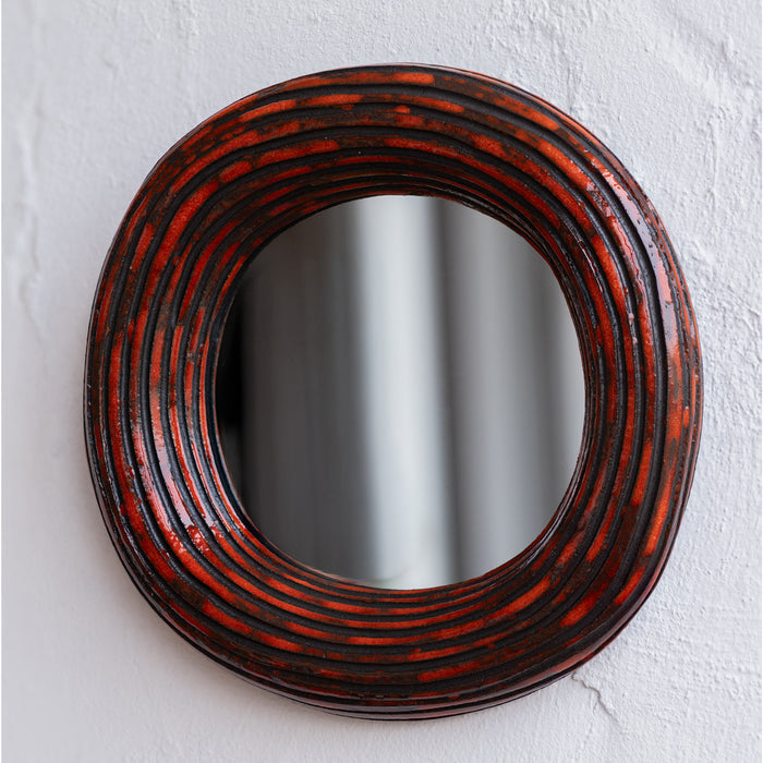 Round mirror with a decorative red and black frame