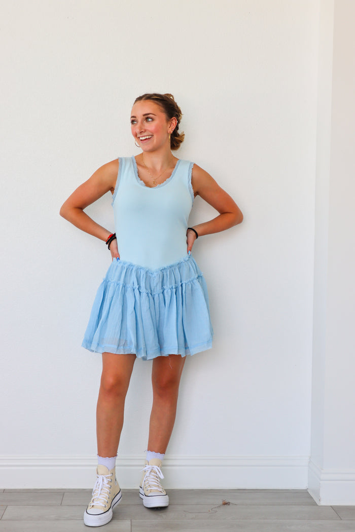 Woman wearing a light blue dress standing against a white wall