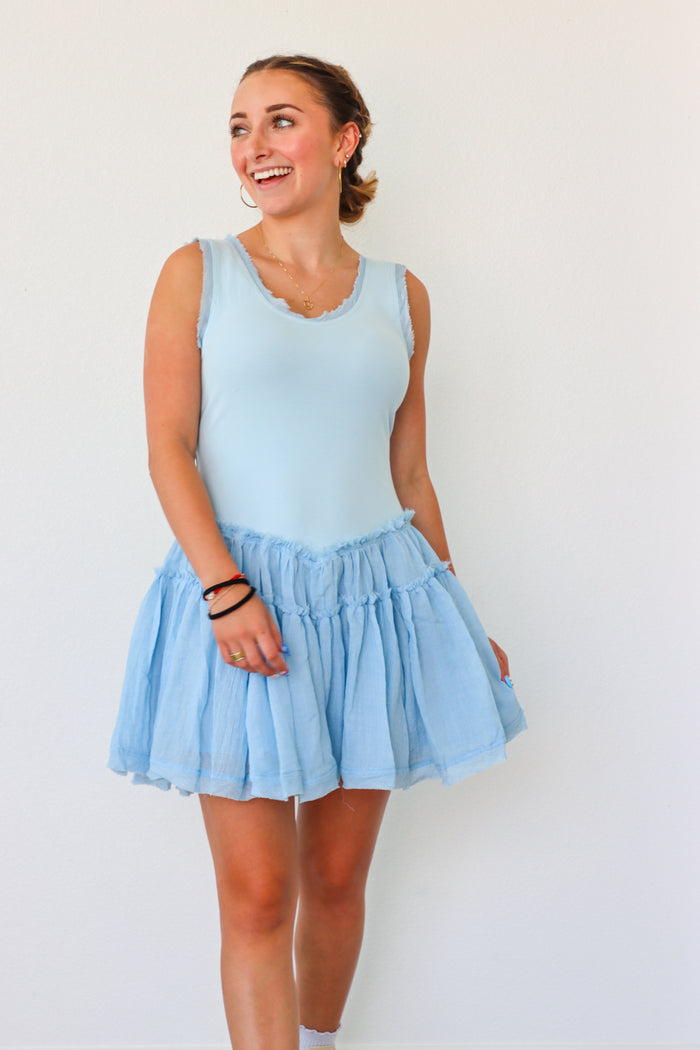 Woman wearing a light blue sleeveless top and skirt against a white background