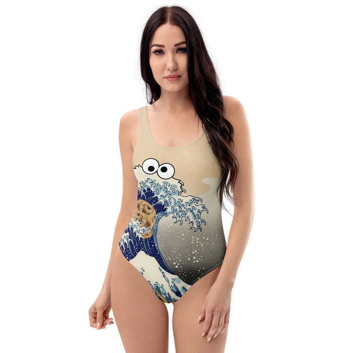 Cookie Wave One-Piece Swimsuit - The specific mutation of the "Great Wave" crest into a shaggy Midnight Indigo (#191970) and Muted Slate Blue (#5D8AA8) puppet silhouette featuring manic googly eyes, with Golden-Brown (#C4915D) chocolate chip cookies tumbling in the trough.