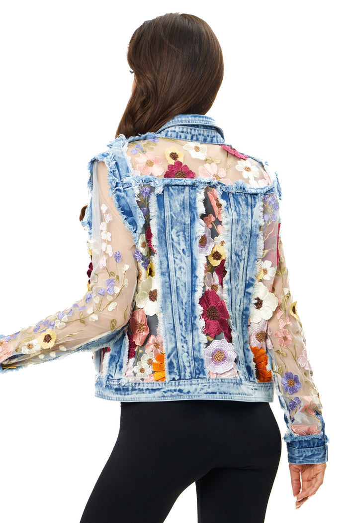 Woman wearing a denim jacket with floral embroidery.