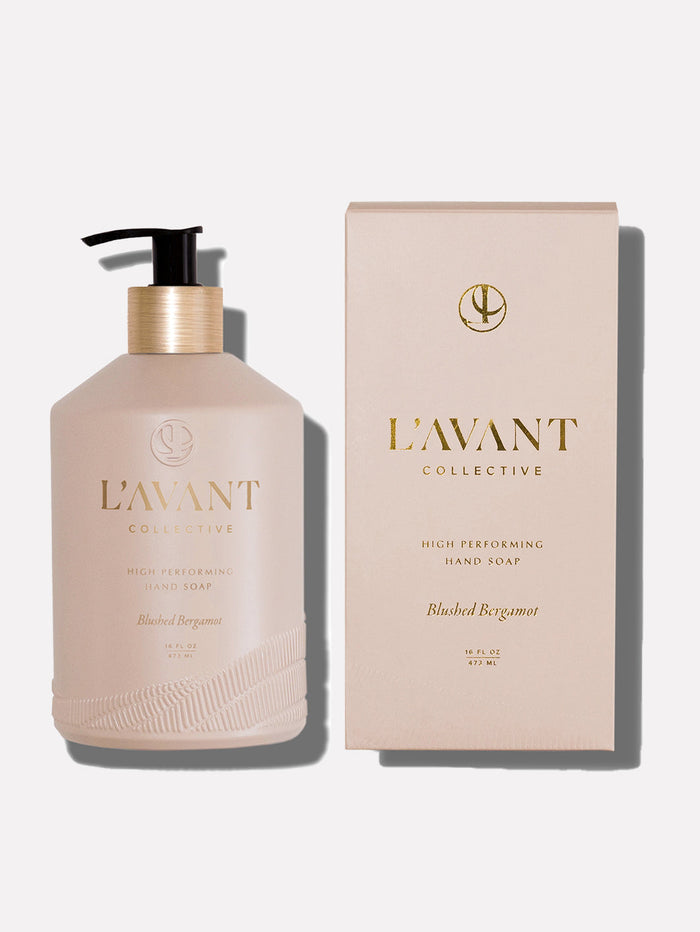 Bottle and box packaging of High Performing Hand Soap - Blushed Bergamot | L'AVANT Collective in a soft blush color with gold lettering, featuring a black pump dispenser on the bottle.