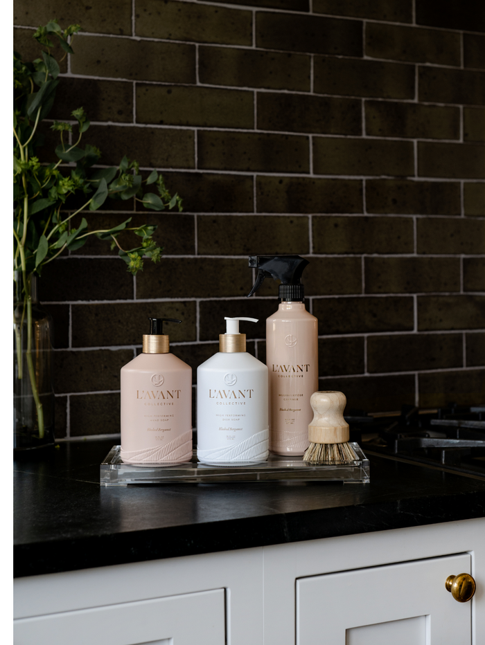 High Performing Hand Soap - Blushed Bergamot | L'AVANT Collective displayed with complementary skincare and body care products on a kitchen counter, promoting a clean and elegant wellness routine.
