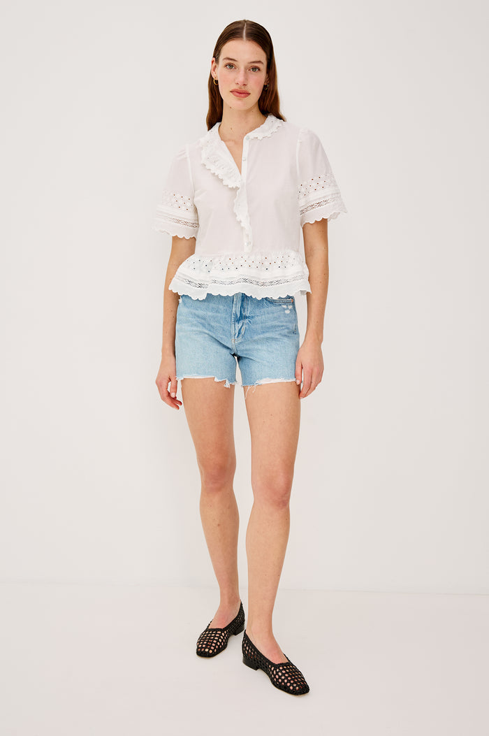 Keeta Shirt in Lightweight Beach Cotton With Ruffled Peter Pan Collar Front Placket Short Sleeves Tiered Hem Crochet Eyelet and Scalloped Trim in White Colorway - Full Body Front View Featured on Model