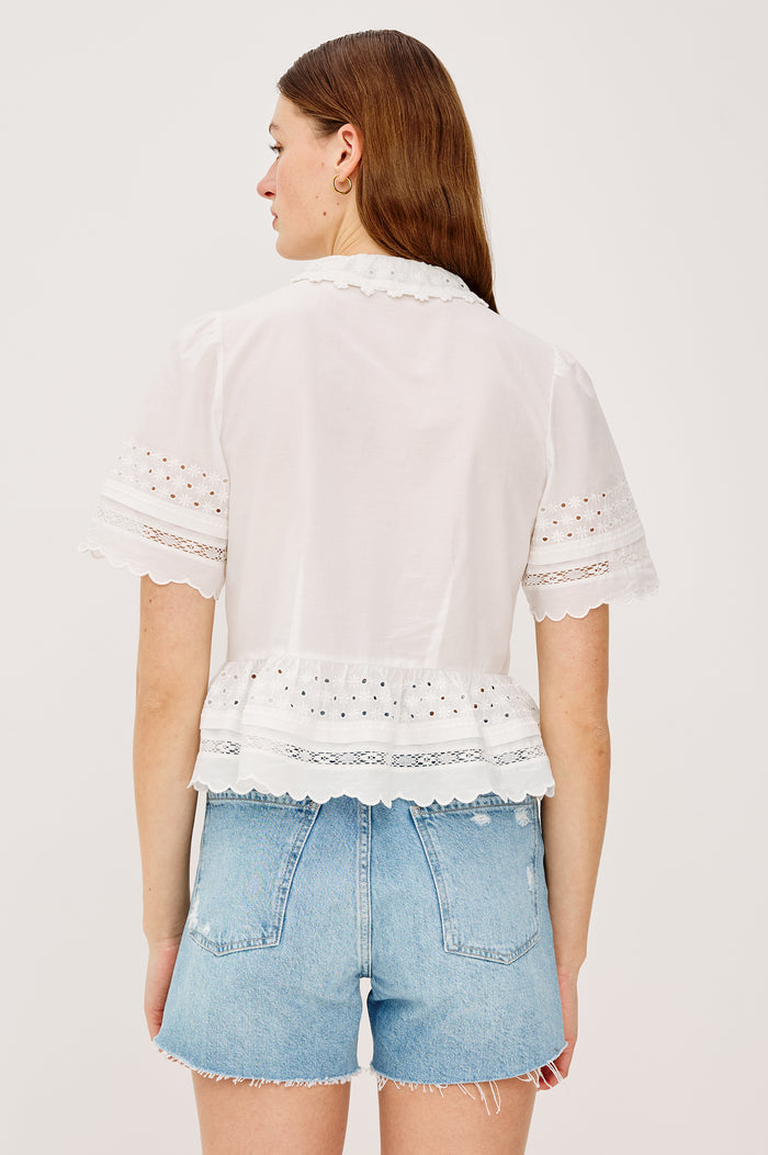 Keeta Shirt in Lightweight Beach Cotton With Ruffled Peter Pan Collar Front Placket Short Sleeves Tiered Hem Crochet Eyelet and Scalloped Trim in White Colorway - Upper Body Back View Featured on Model