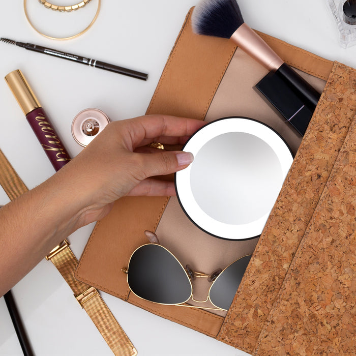 Zadro LED15X 705004419499 environment photo front view user removing from small makeup bag, lighted compact mirror with magnification & suction cups in front of a real life setting