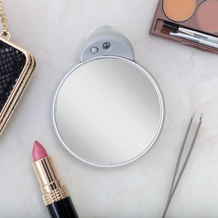 Zadro FC30L 705004417938 environment photo front view on vanity table with makeup products, lighted compact travel mirrors with magnifications & suction cup in front of a real life setting