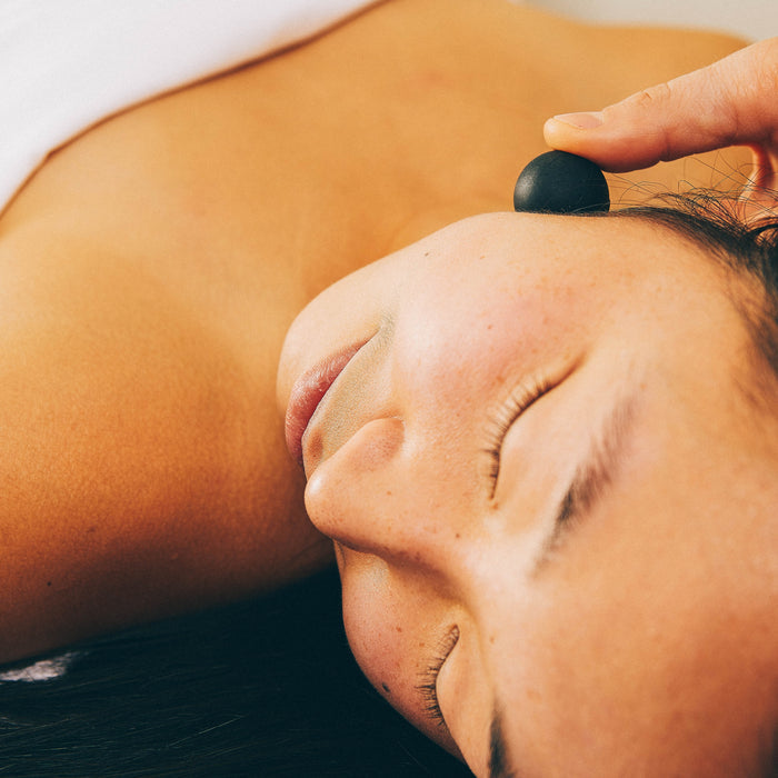 Close-up of a person receiving a relaxing facial massage using a black Micro Rounds | RAD tool near the ear, highlighting wellness and body care benefits.