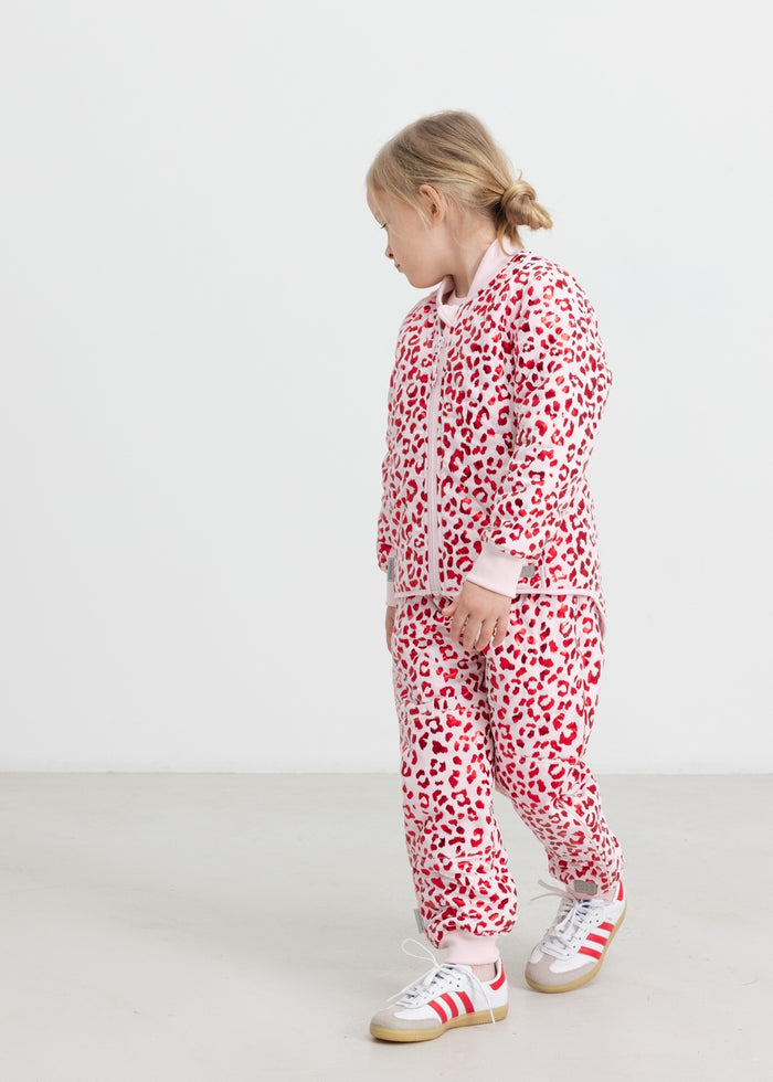 Children wearing bright red thermal pants and a leopard print jacket.