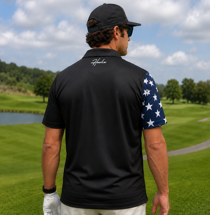 Man on golf course facing away wearing a patriotic Men's Golf Polo in Black with American flag design with Declaration of Independence overlay on the polo.