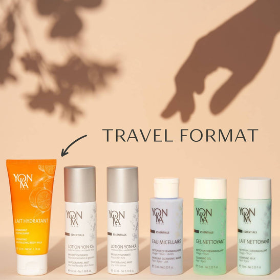 Travel Lait Nettoyant | Yon-Ka Paris travel size bottle among a collection of skincare products displayed against a warm beige background with soft shadows.